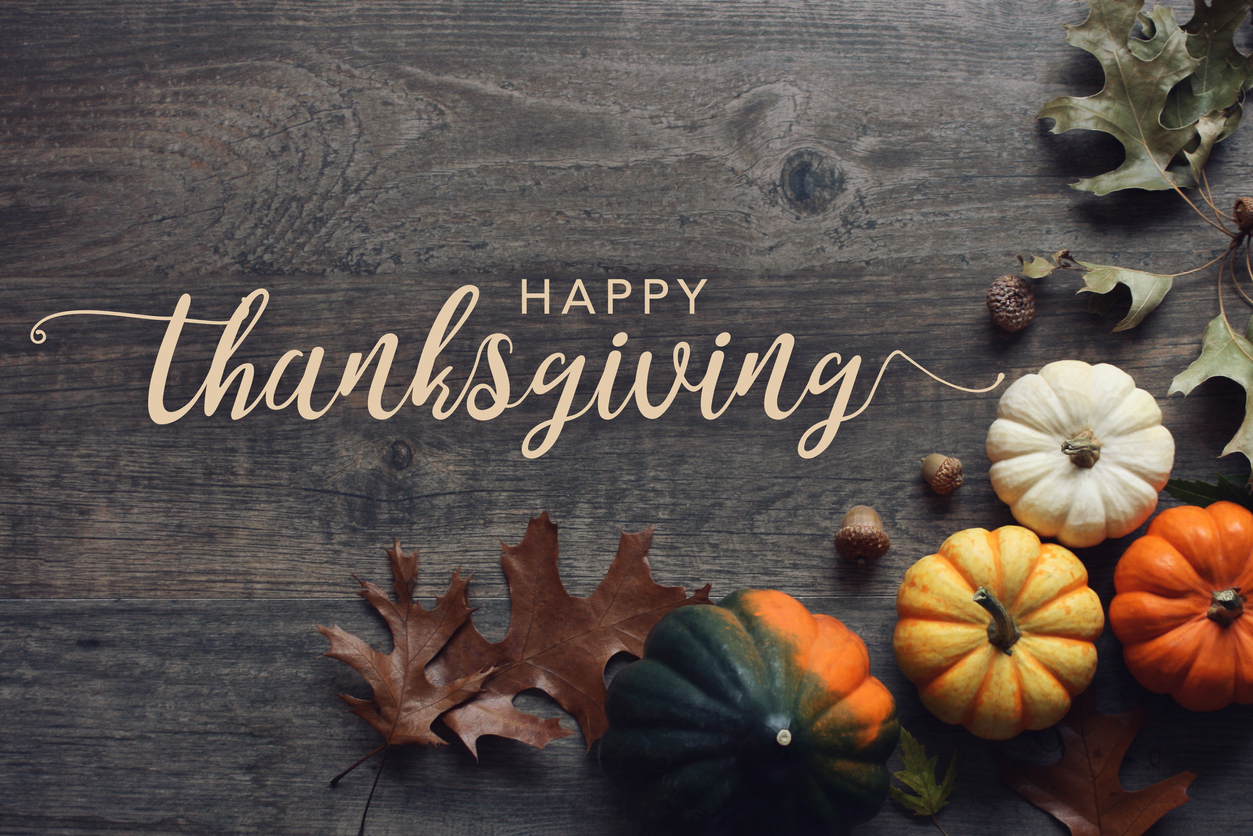 Happy Thanksgiving greeting text with fall pumpkins, squash and leaves over dark wood background Happy Thanksgiving greeting text with fall pumpkins, squash and leaves over dark wood table background